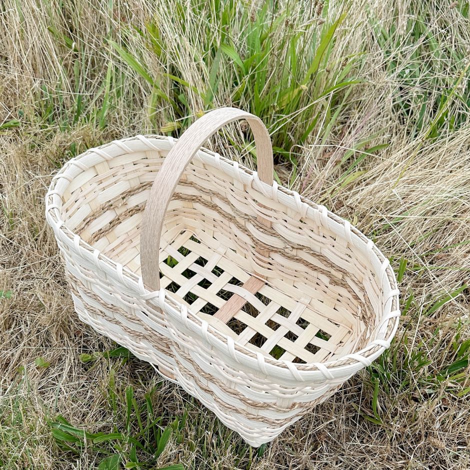 Market basket with an open weave base sitting in the grass.