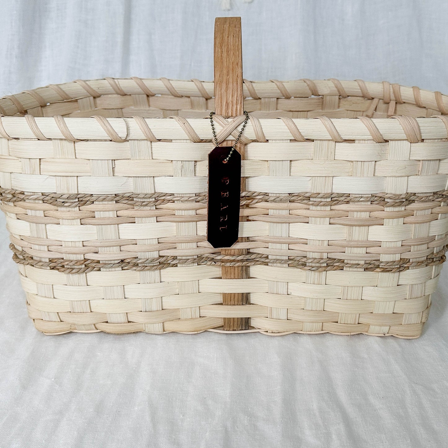 Woven basket with a wooden handle on a white background