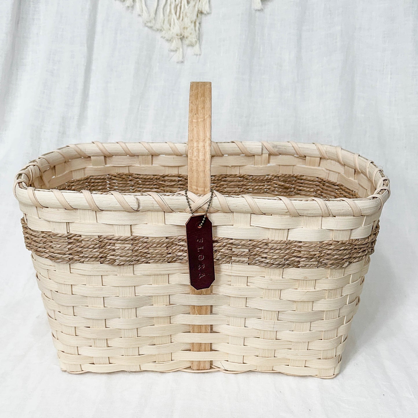 Woven basket with a wooden handle on a textured white surface