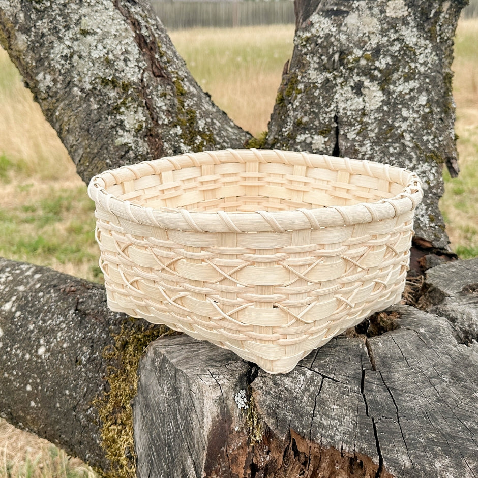 Cross-stitch napkin basket sitting on a tree stump.