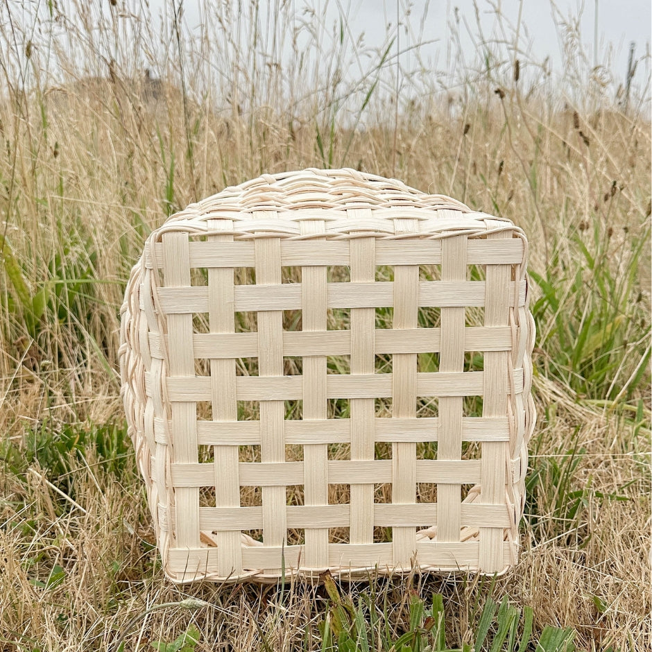 Bottom view of the cross-stitch napkin basket sitting on a tree stump.