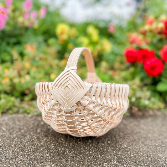 Melon basket sitting on a garden path with a flower bed in the background.