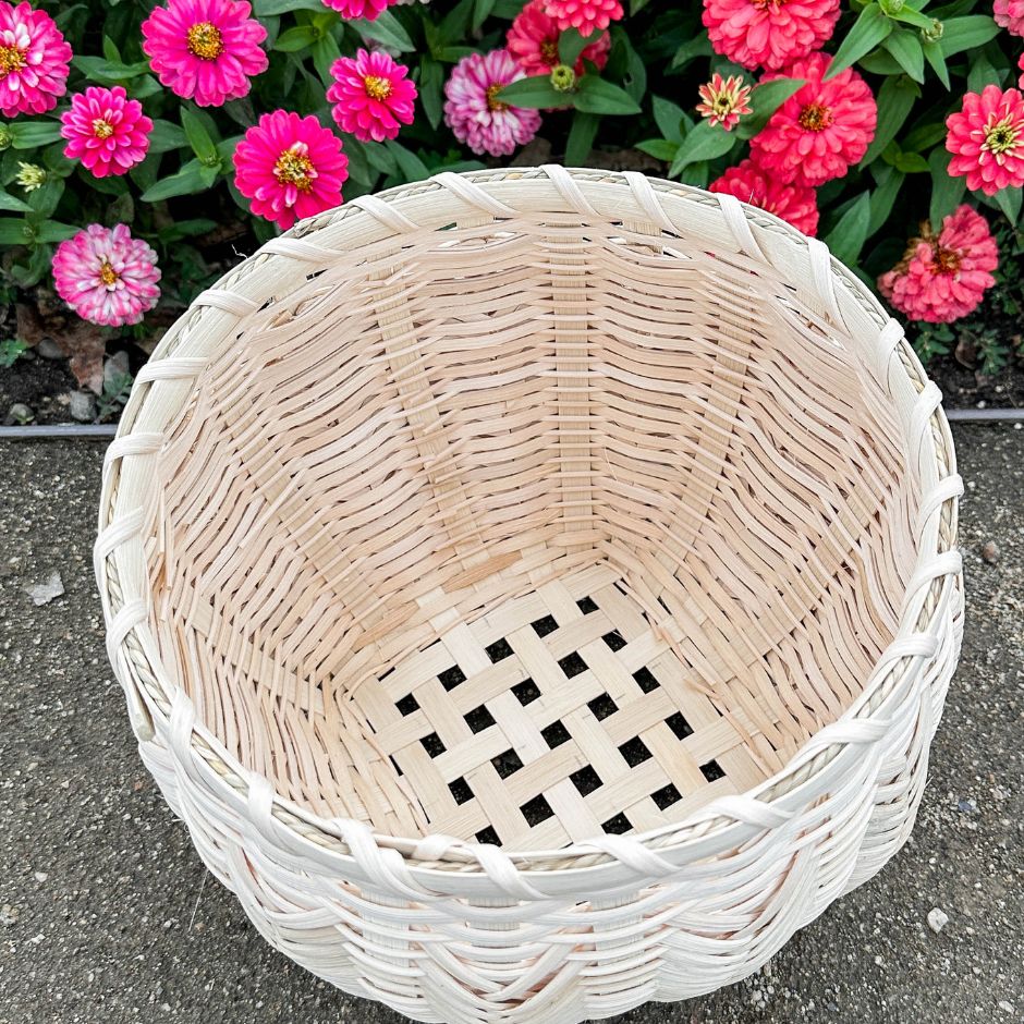Catshead basket with detailed view of the inside sits against a flower garden.