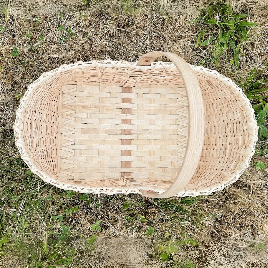 Top view detail of a woven market basket sitting in the grass.
