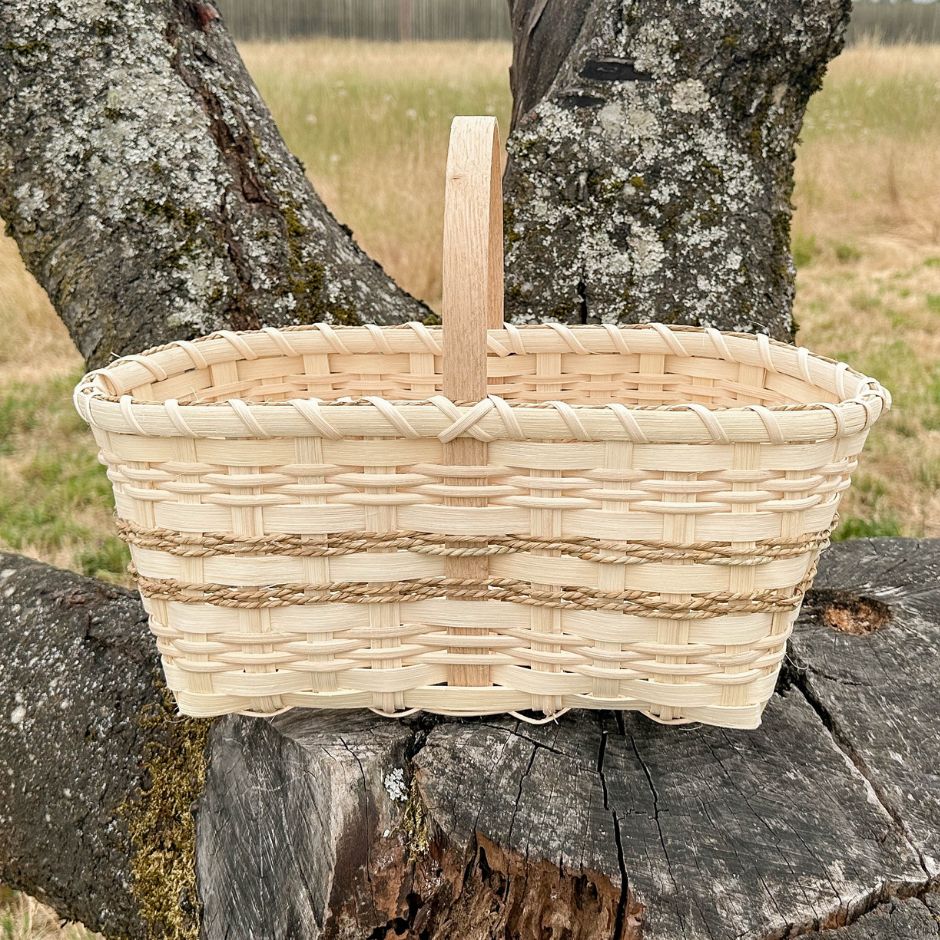 Rattan market basket with seagrass detailing resting on a tree stump.