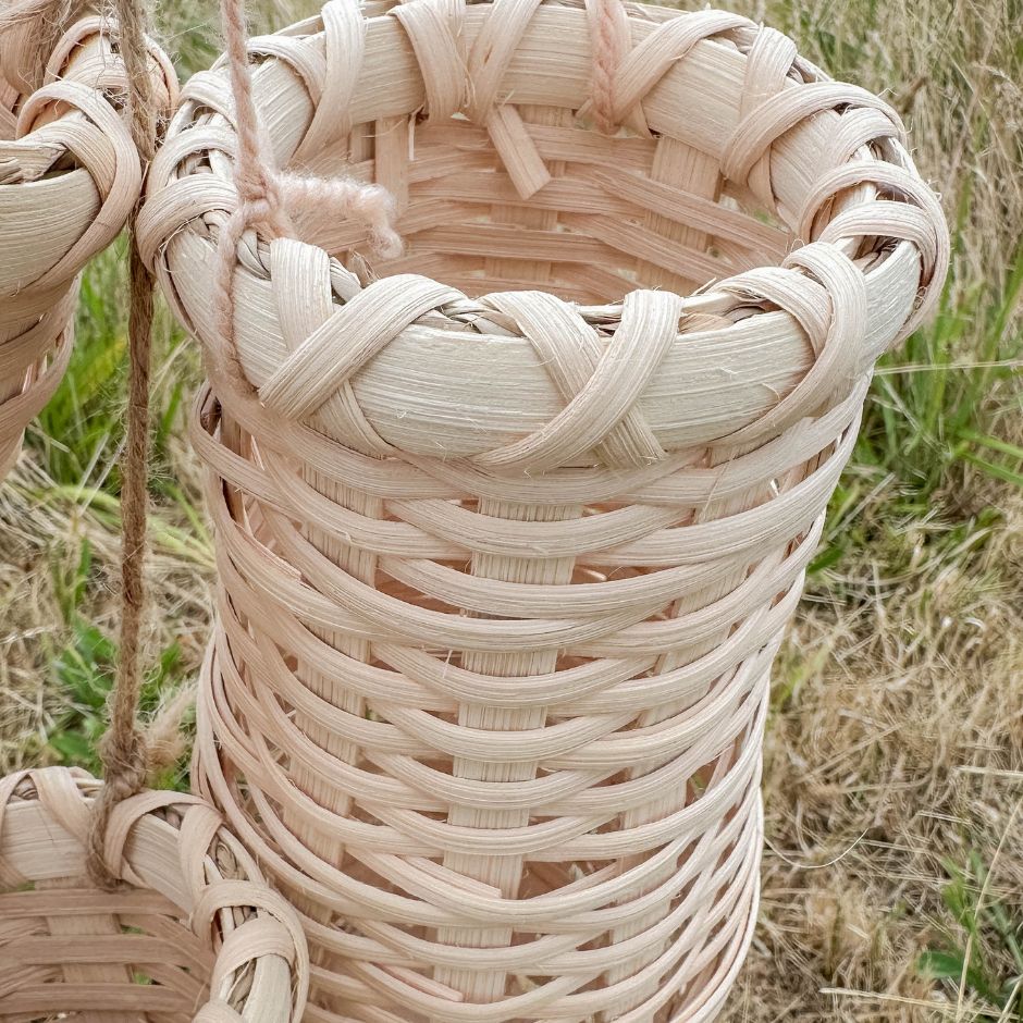 Close-up of a woven basket with natural fibers against a grassy background.