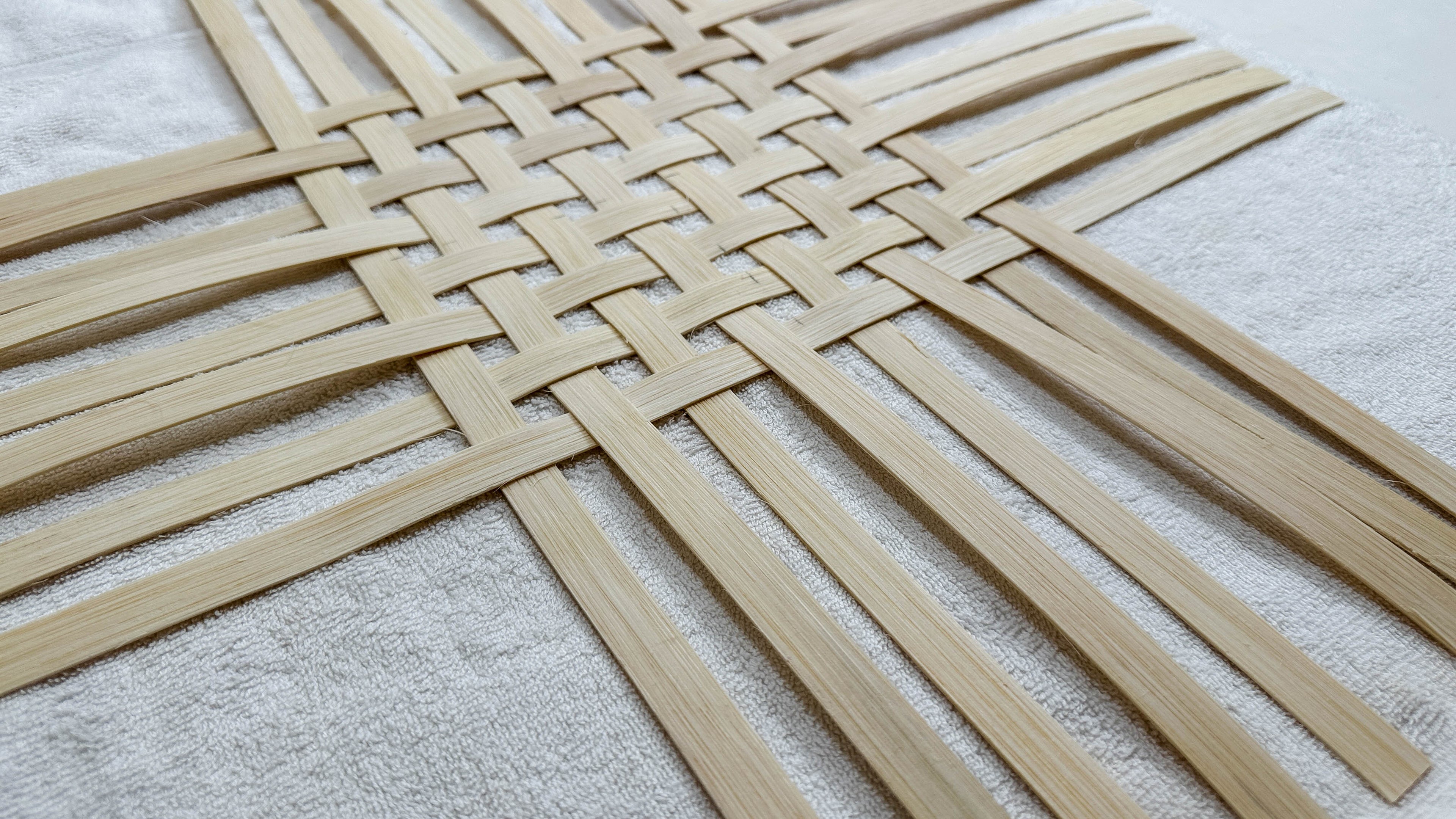 Load video: A woman weaves a rattan reed basket.