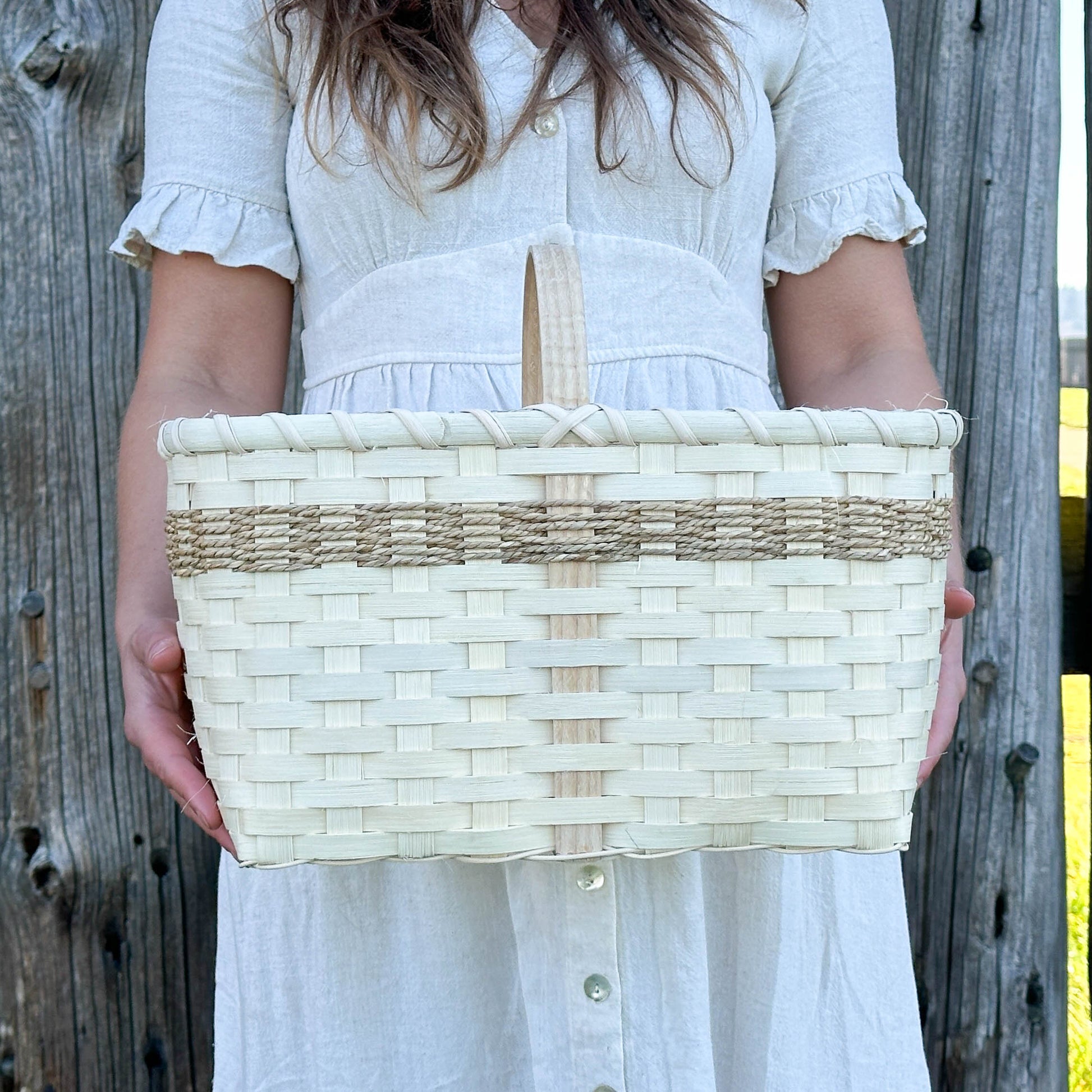 Woman holding a woven basket against a wooden fence background