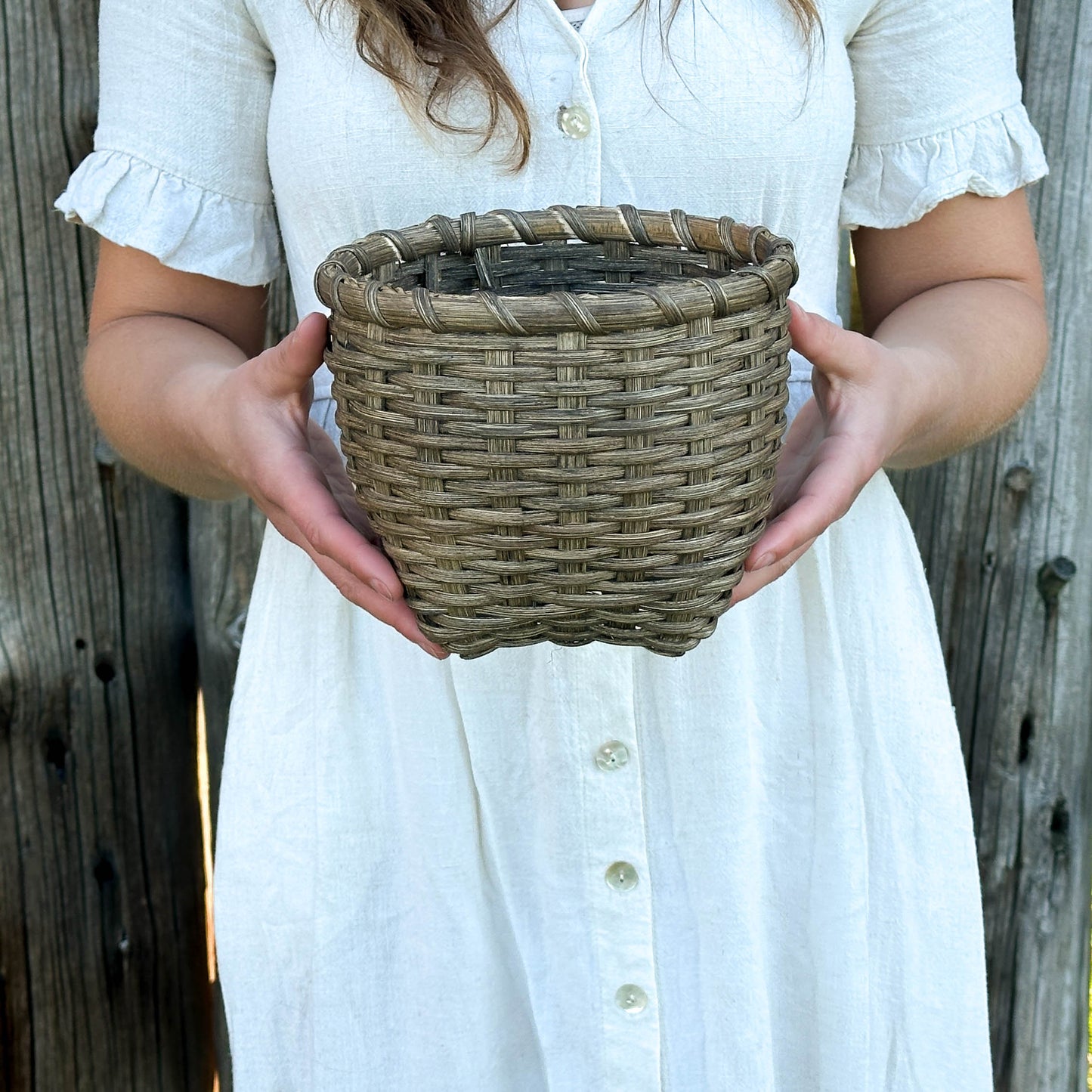 Person holding a woven basket against a wooden background