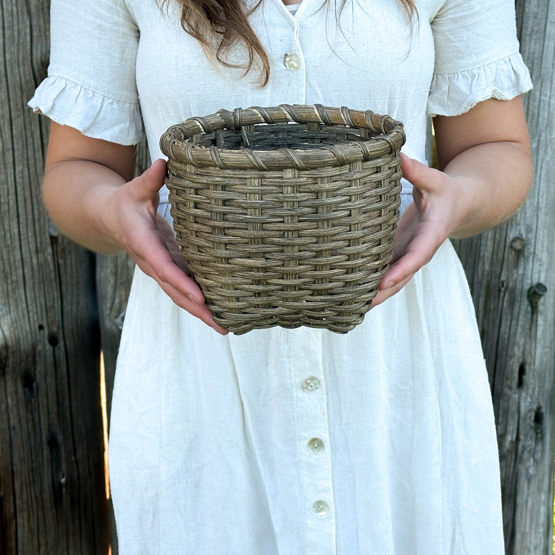 Person holding a woven basket against a wooden background