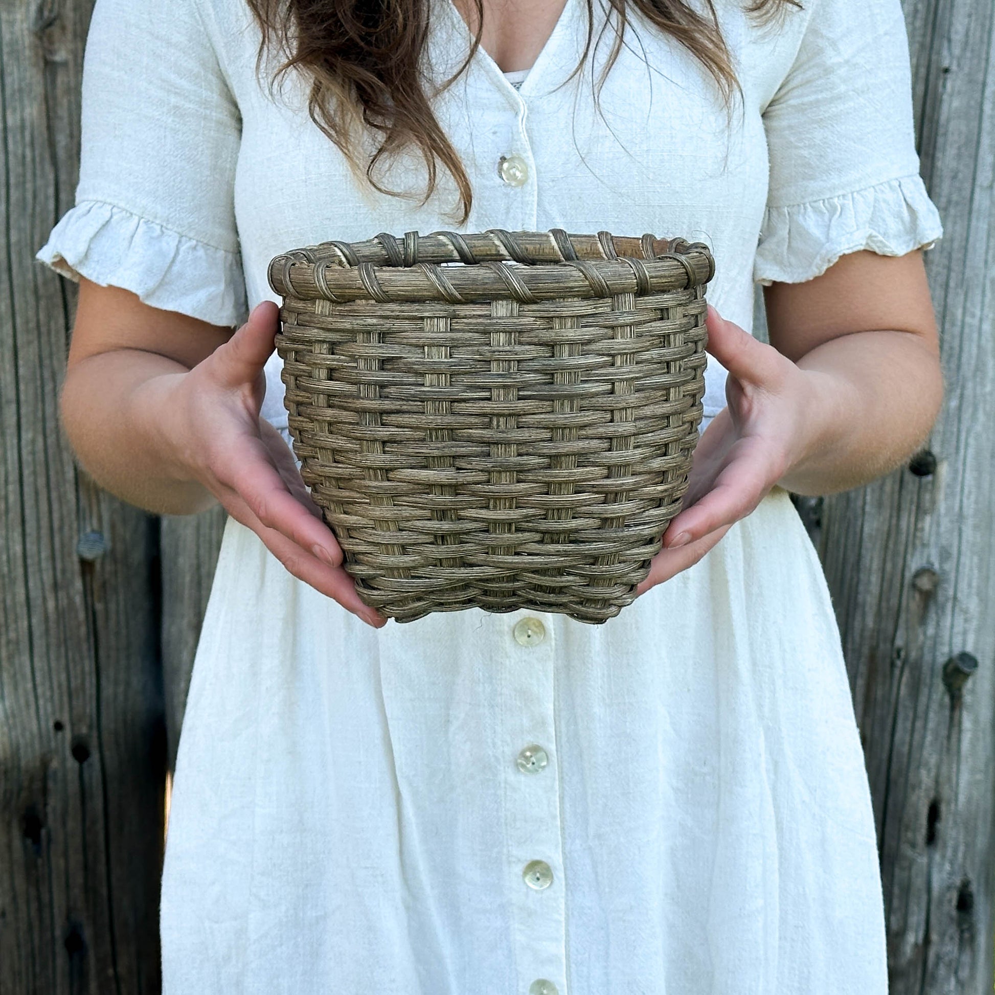 Person holding a woven basket against a wooden background