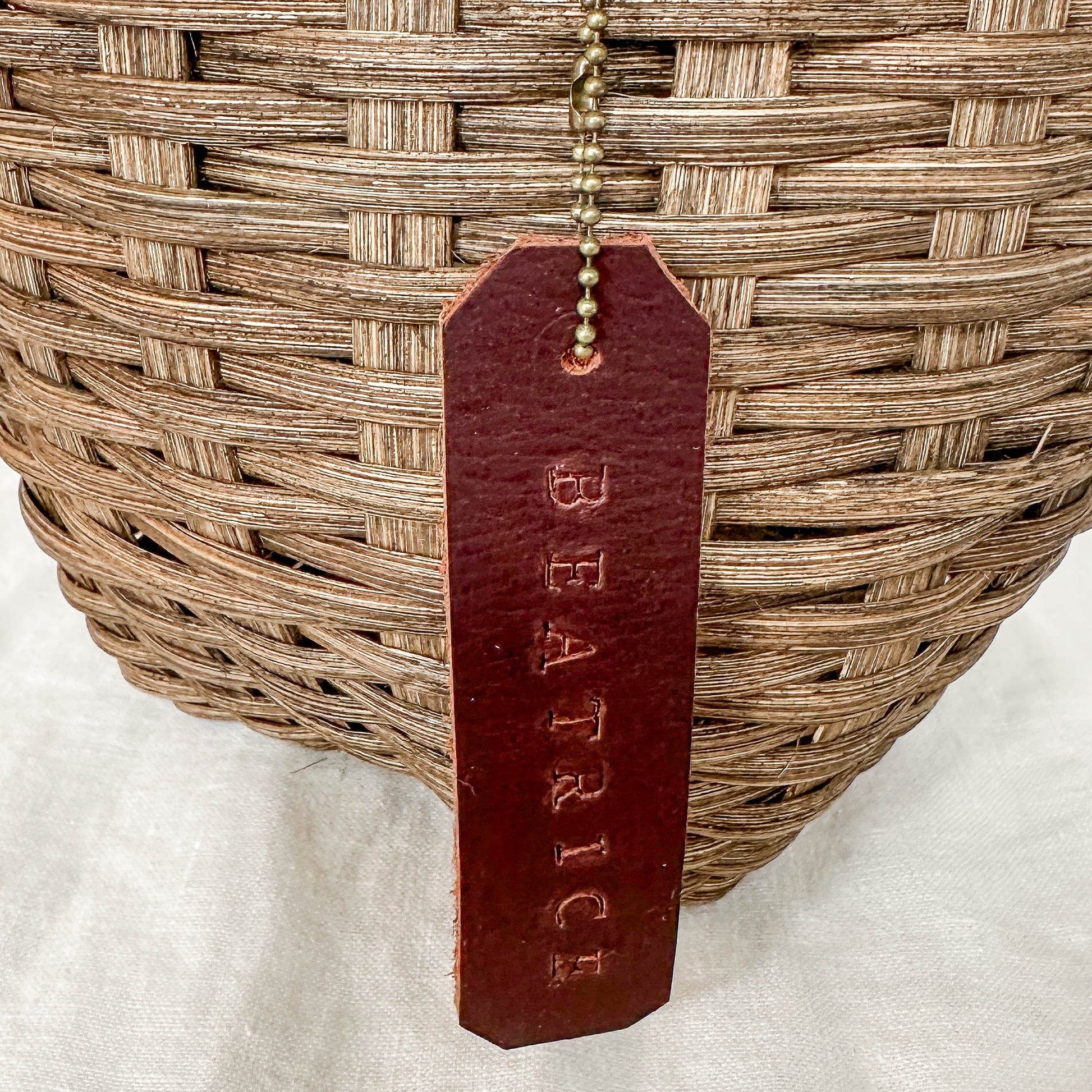 Woven basket with a leather tag labeled 'Beatrice' on a white background