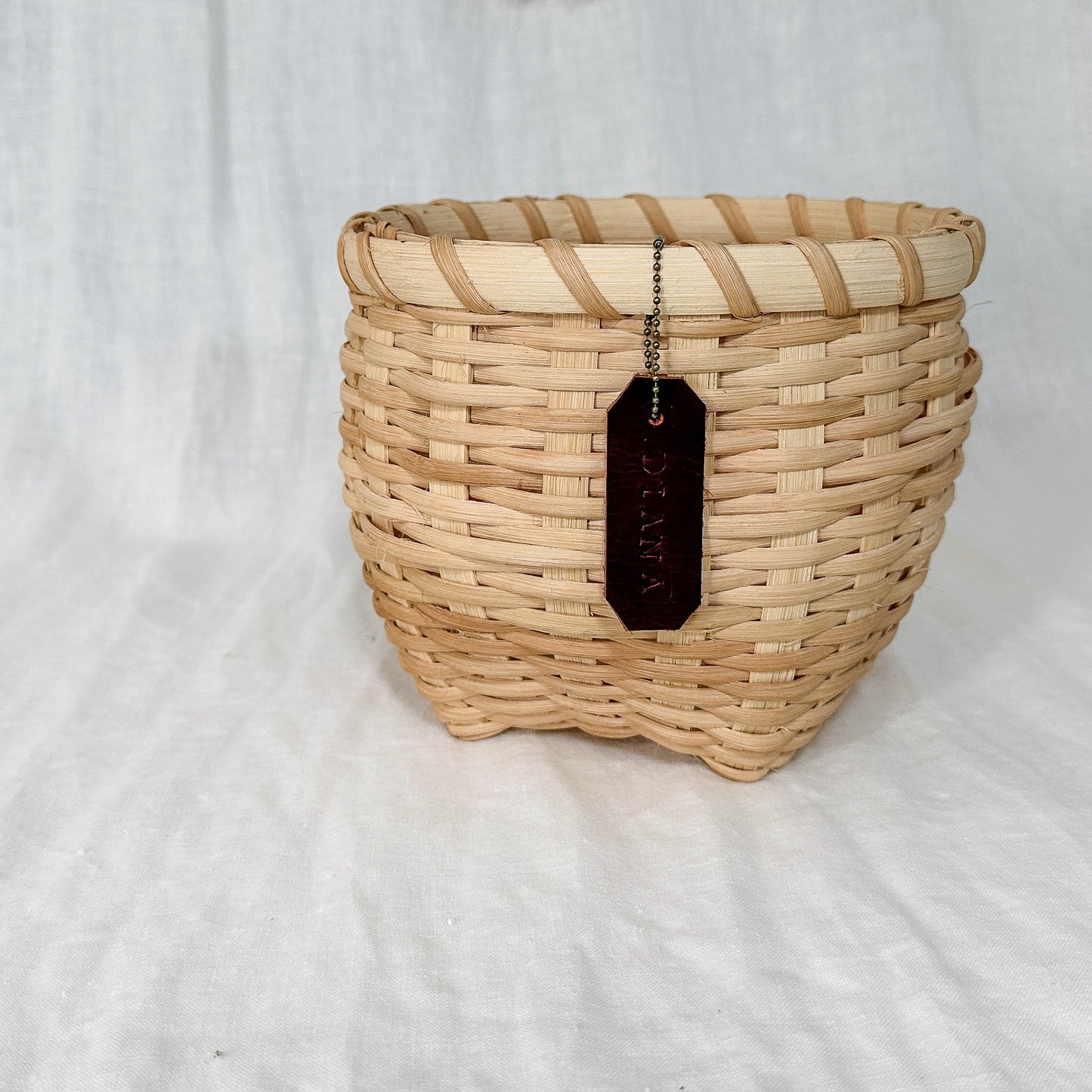 Woven basket with a tag on a white fabric background