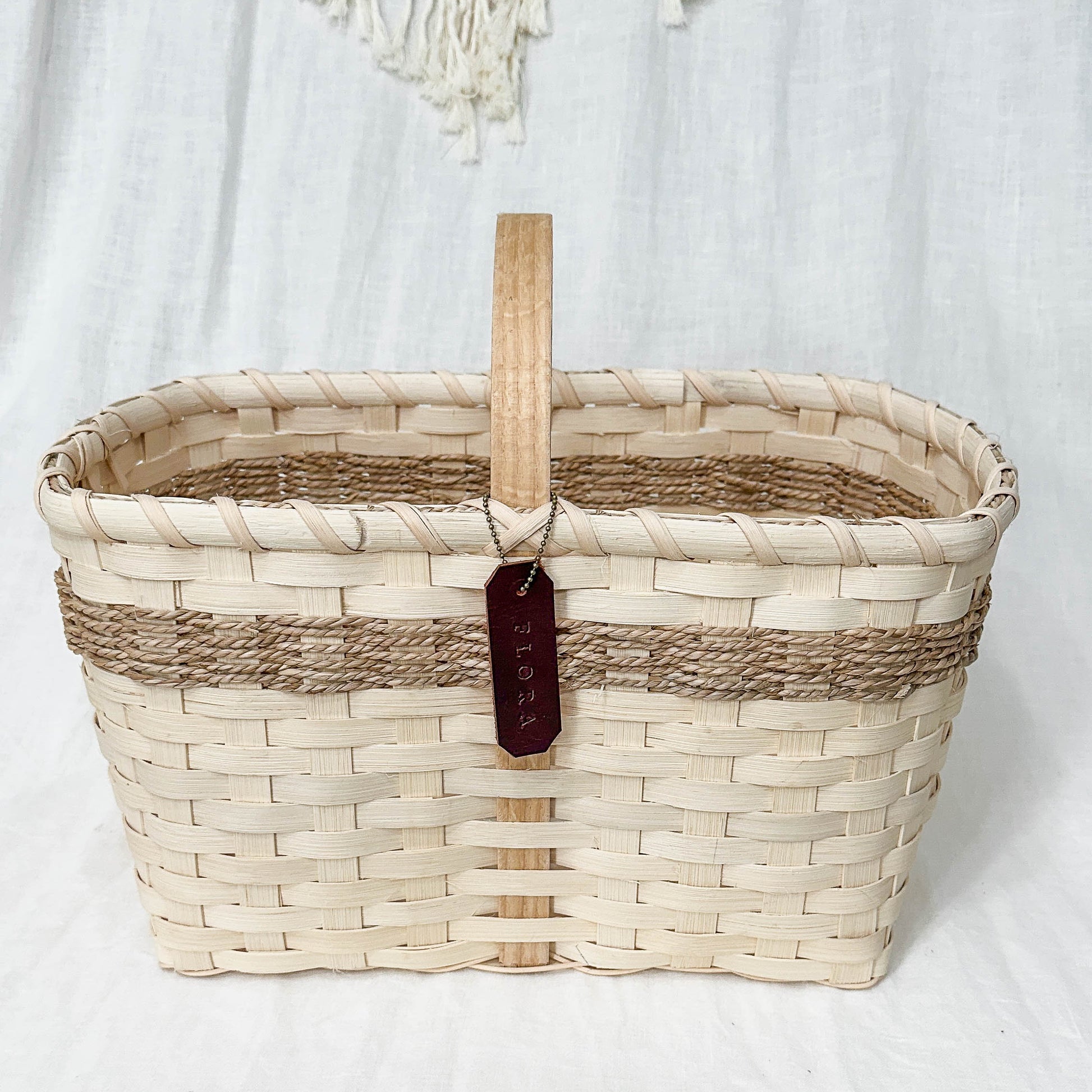 Woven basket with a wooden handle on a textured white surface
